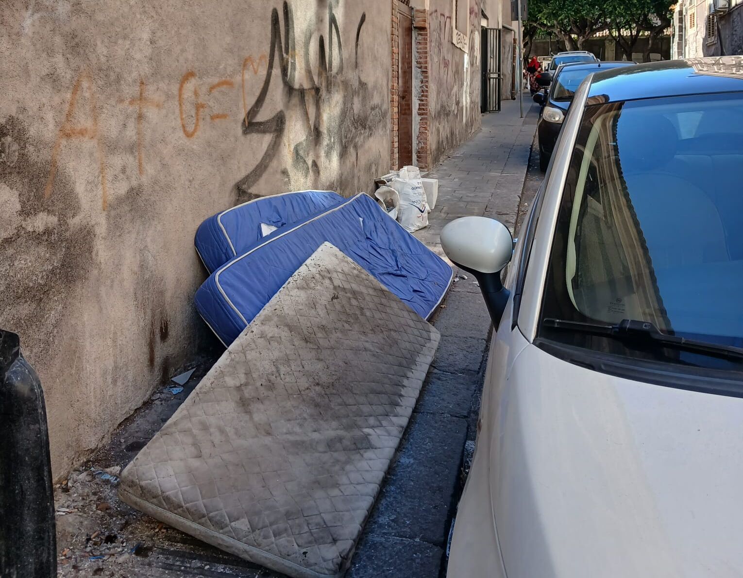 discarica abusiva Catania, materassi e rifiuti sul marciapiede vicino Università